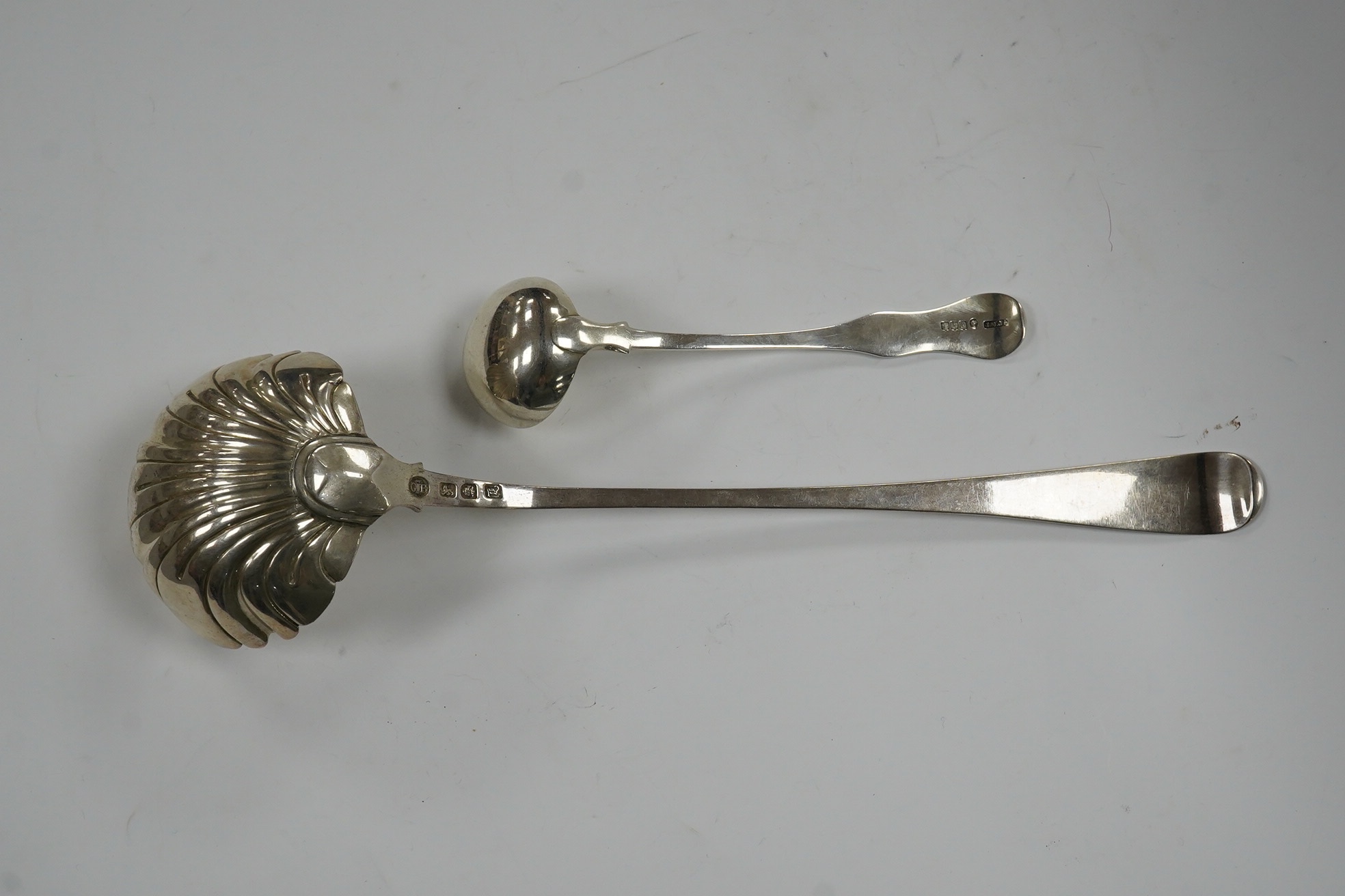 An early George III silver Old English feather edge pattern soup ladle, George Baskerville, London, 1766, together with a Victorian Scottish silver sauce ladle, 6.1 oz. Condition - poor to fair
